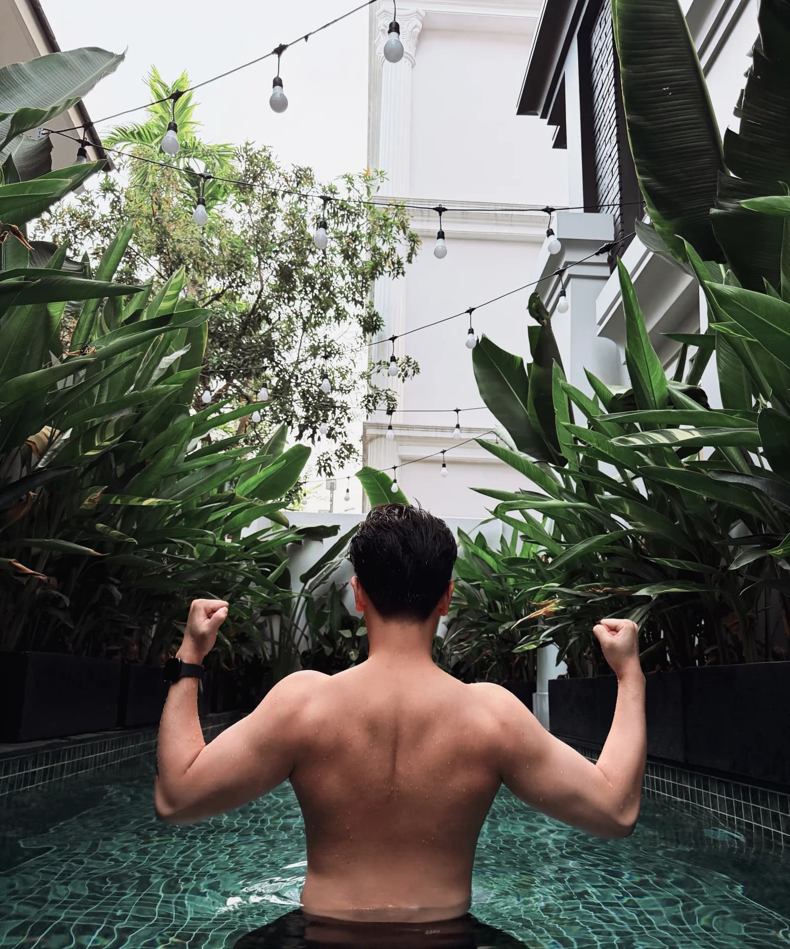 Khanh Duy posing by a pool surrounded by tropical plants